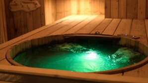 A wooden sauna with a green-lit interior, wooden walls, and a bench. - Gite Finistère for 7: Private Pool & Spa, Garden, 4 km from Beaches (PEUMERIT)