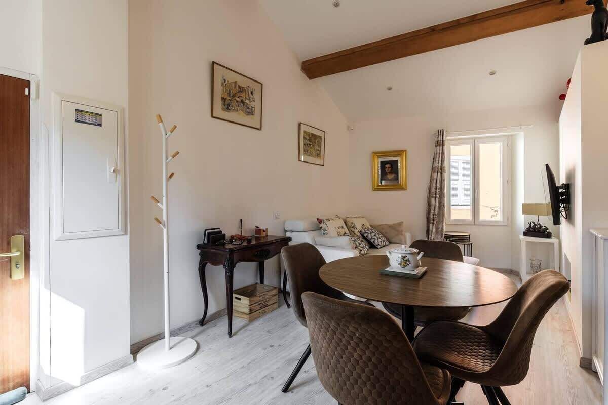 A dining area with a round table, chairs, a coat rack, and a sofa.