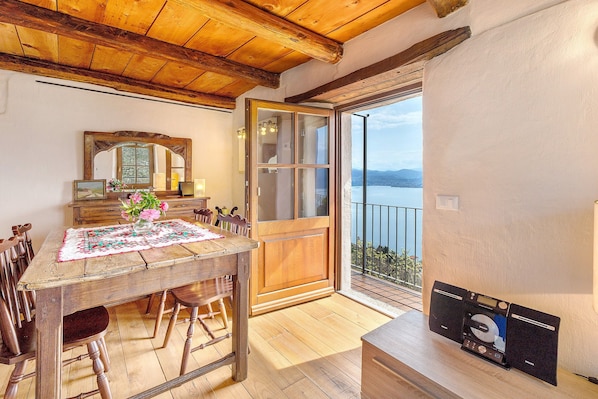 A wooden dining table with chairs, a wooden cabinet, a mirror, and a view of the sea.
