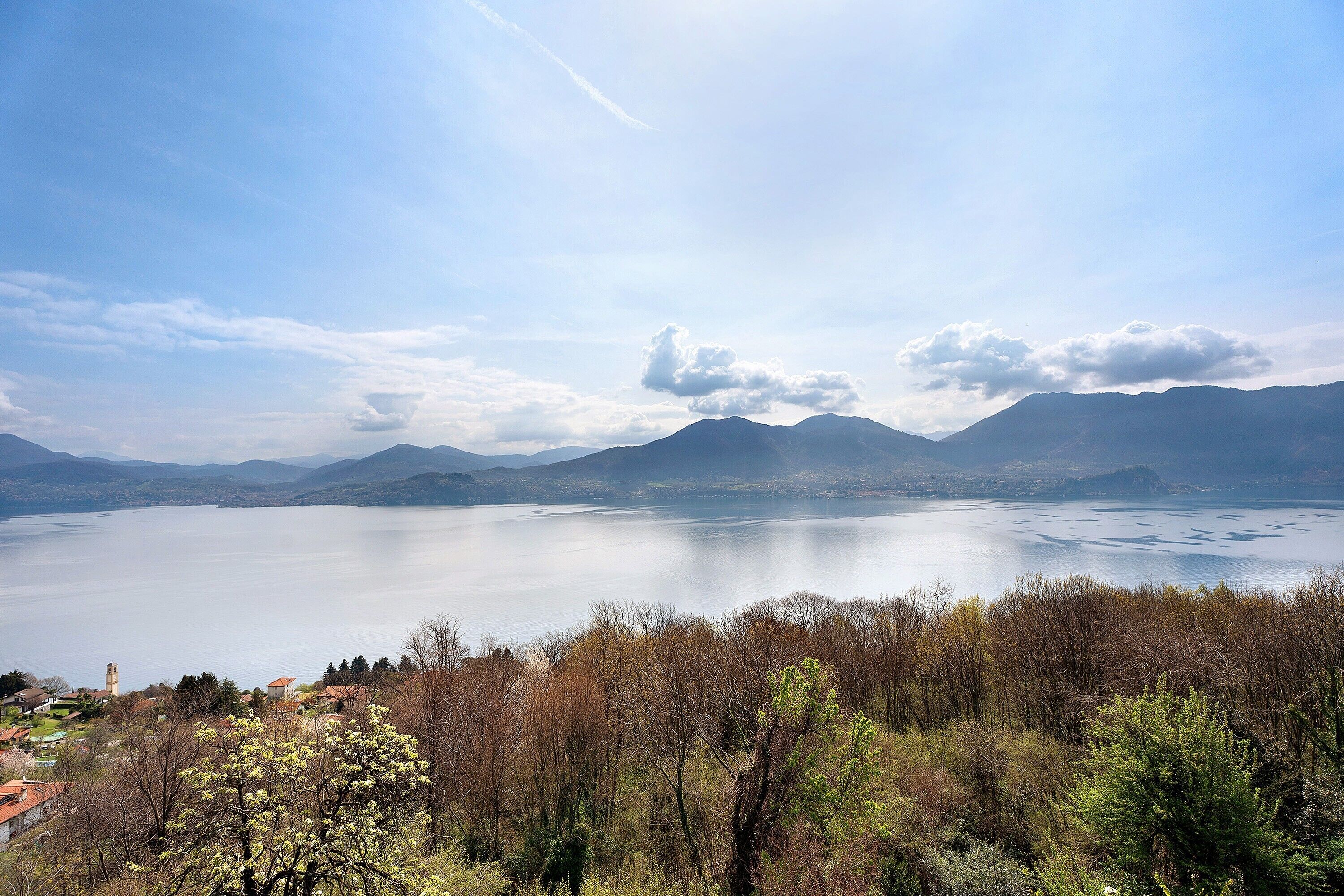 A lake surrounded by mountains, a clear sky, and trees in the foreground.