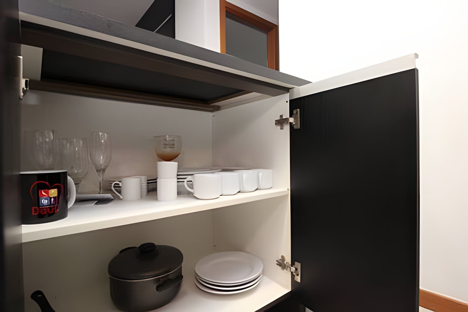 A compact kitchen with a microwave, coffee maker, and stacked plates.