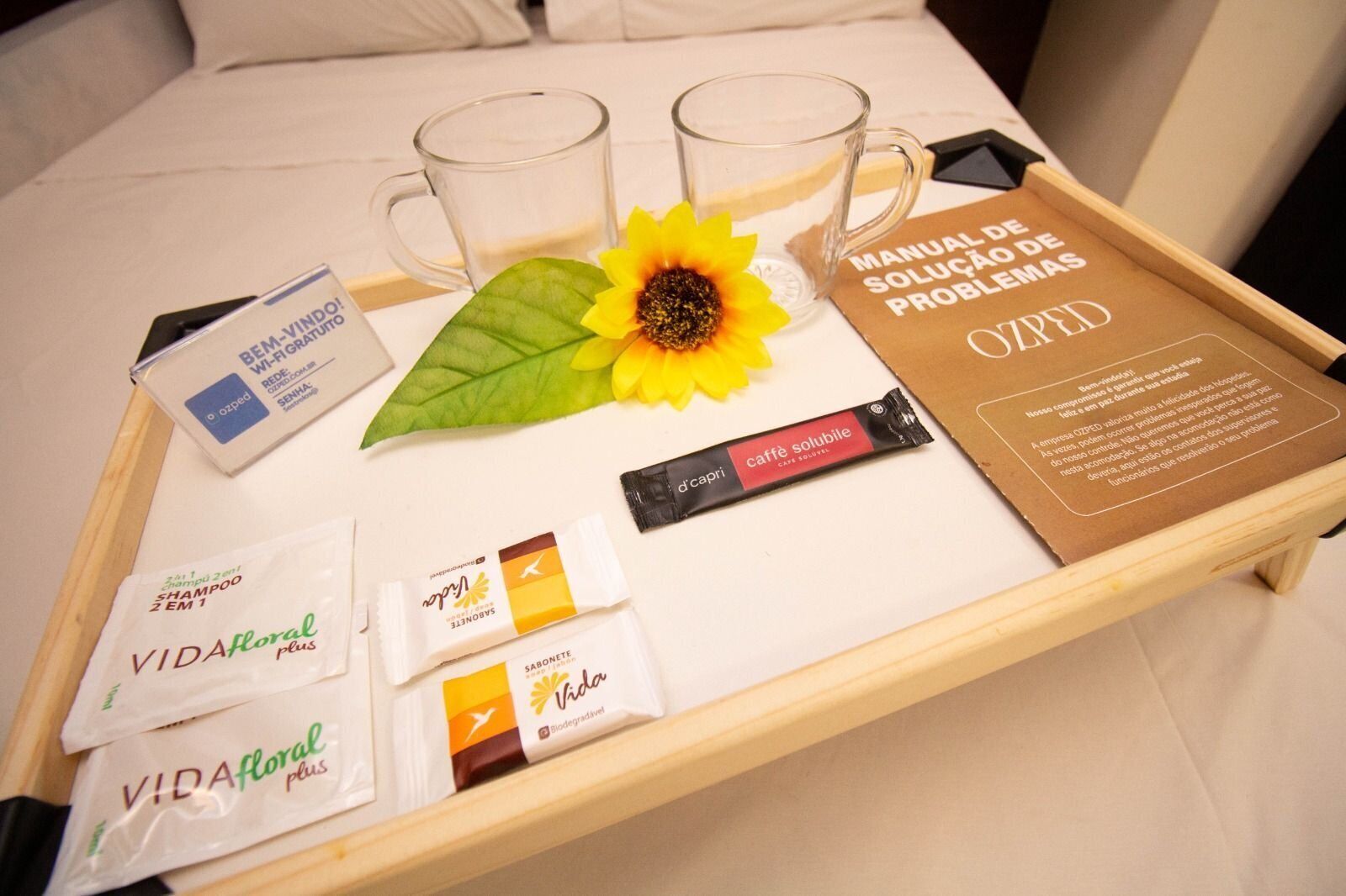 A hotel room tray with toiletries, a manual, and a sunflower.