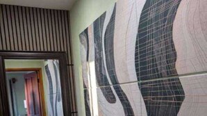 Un passadís amb un mur amb dibuixos, una catifa i un mirall que reflecteix l'habitació.
