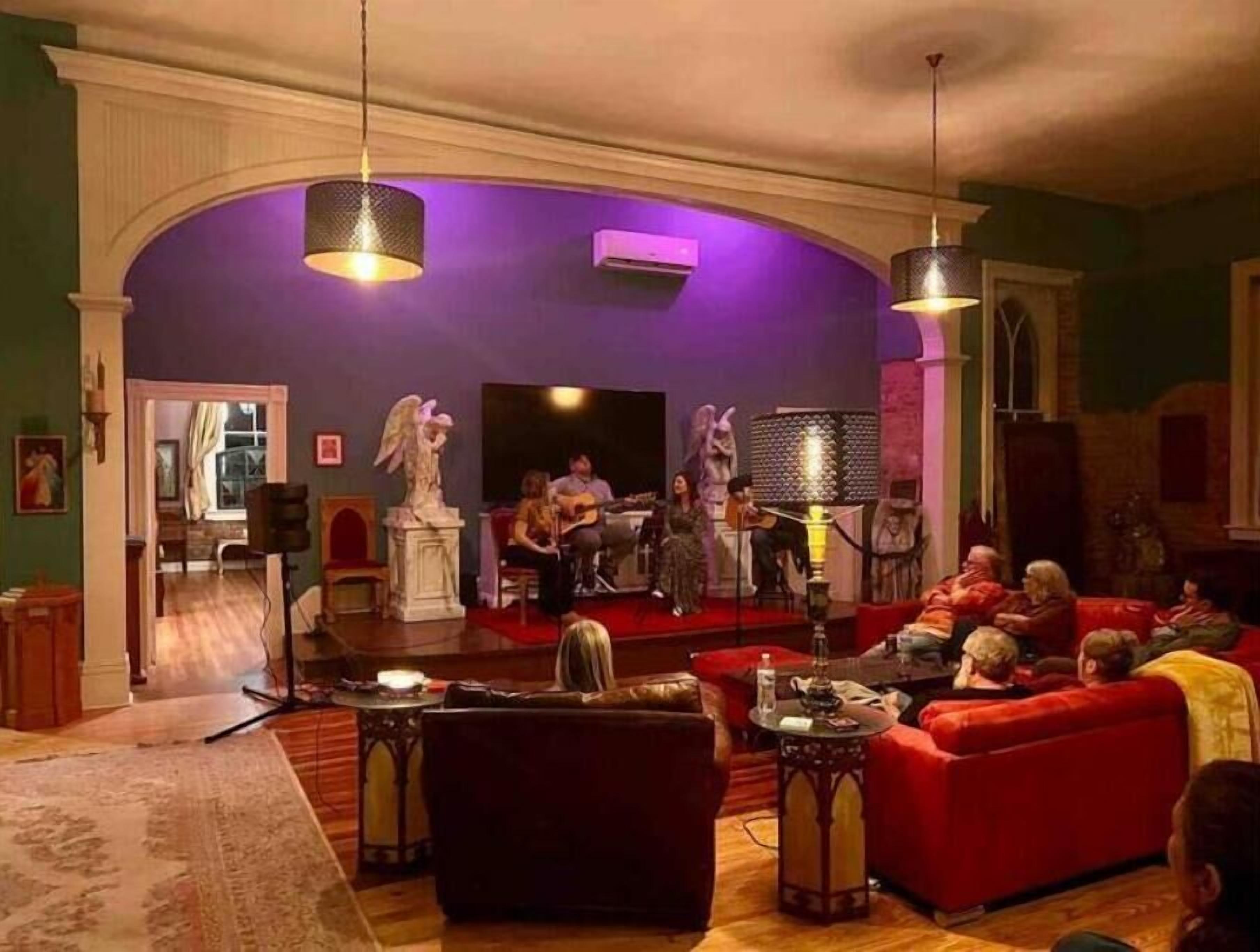 A living room with a stage, red sofas, and a statue.