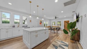 A modern kitchen with white cabinetry, pendant lighting, and a large island. - Mid Century Modern Retreat by Coffee Food + Shops (Tampa)