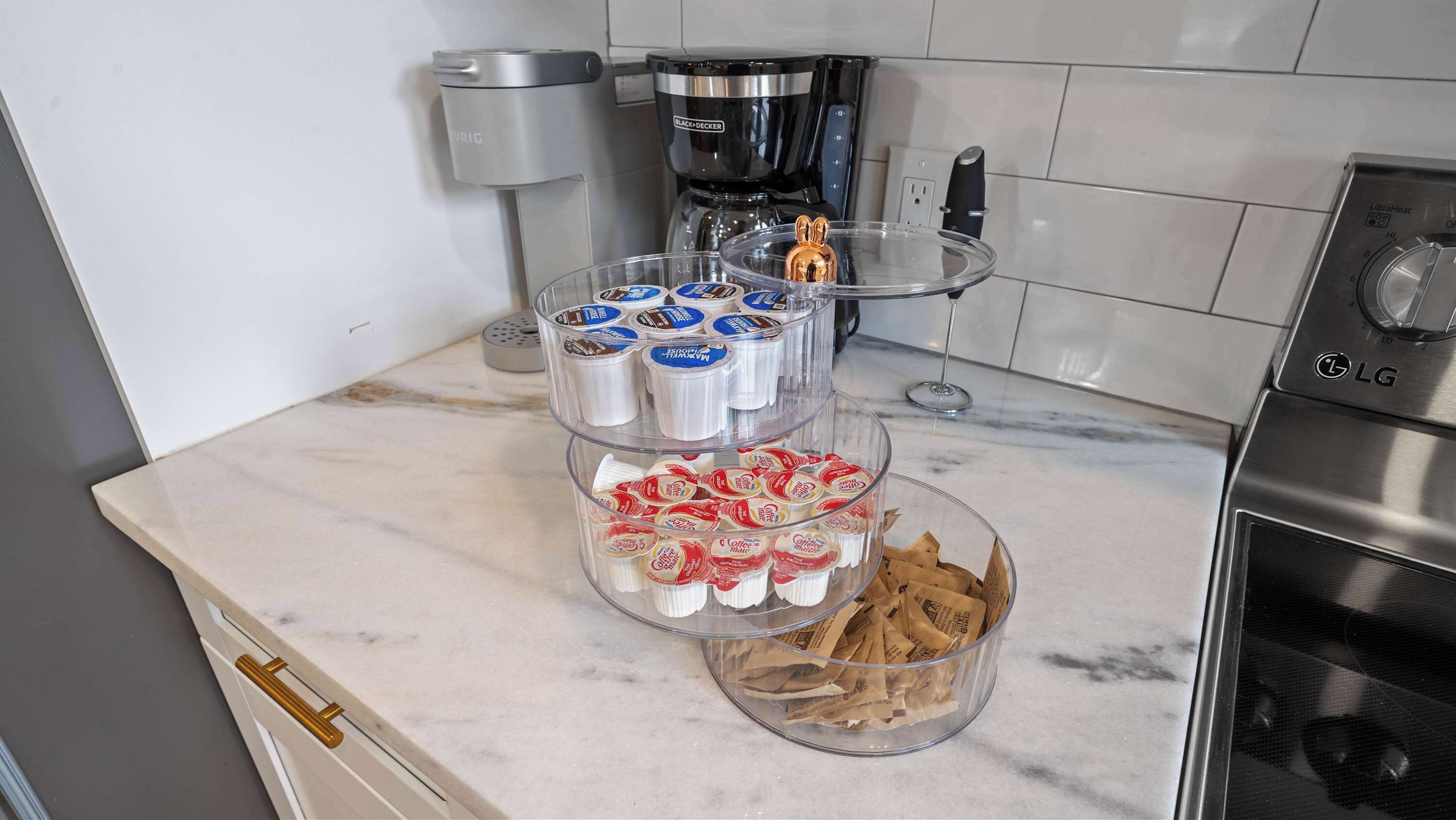 Una encimera de cocina con una cafetera, un preparador de café y un dispensador de café.