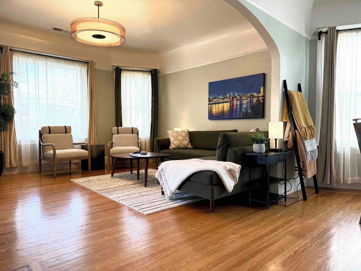 A well-lit living room with a sofa, chairs, a coffee table, and a painting on the wall.