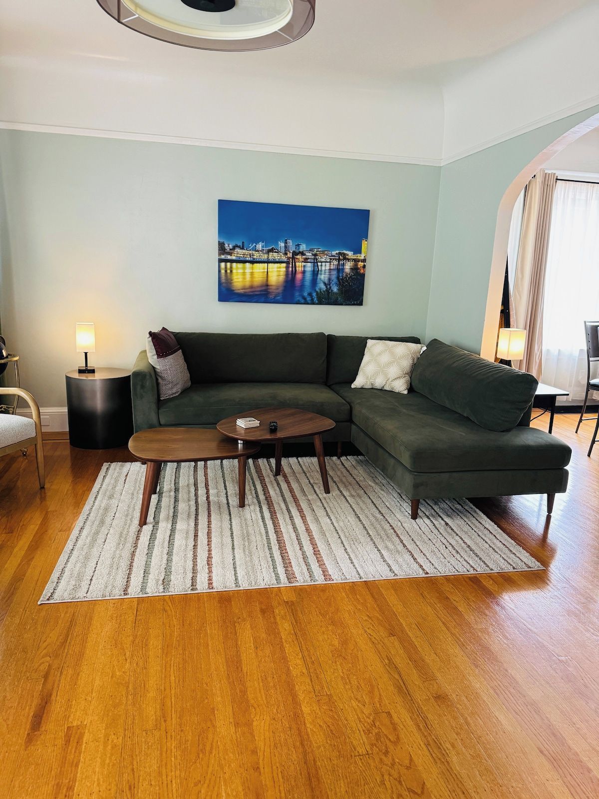 A living room with a sectional sofa, a coffee table, a lamp, and a painting on the wall.
