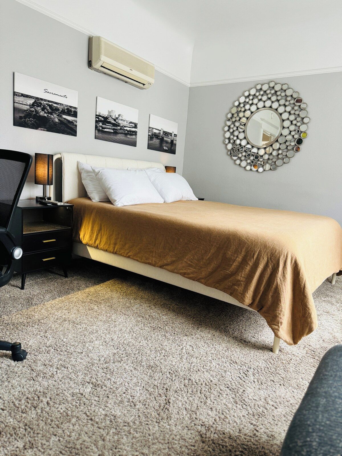 A bedroom with a bed, a nightstand, a lamp, and wall-mounted pictures.