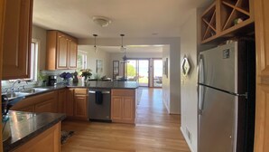 A modern kitchen with wooden cabinets, stainless steel appliances, and a view to the outside. - Stunning Lakefront Beach House (Hilton)