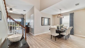 A spacious dining area with a wooden table and chairs, a ceiling fan, and a view of the outdoors. - Spacious 5 Bedroom Villa w/ Themed Bedrooms, Theater Room, and Free Pool Heat (Kissimmee)