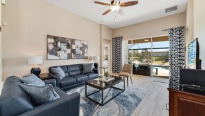 A modern living room with a sofa, coffee table, and artwork on the wall. - Spacious 5 Bedroom Villa w/ Themed Bedrooms, Theater Room, and Free Pool Heat (Kissimmee)