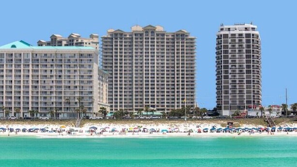 A beachfront hotel with multiple high-rise buildings, a sandy beach, and umbrellas. - Ariel Dunes I Unit 1304 at Seascape for 7 people (Miramar Beach)