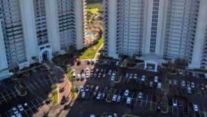A high-rise residential building with multiple balconies, a parking lot, and a view of the ocean. - Ariel Dunes I Unit 1304 at Seascape for 7 people (Miramar Beach)