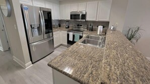 A modern kitchen with white cabinets, stainless steel appliances, granite countertops, and a built-in oven. - Ariel Dunes I Unit 1304 at Seascape for 7 people (Miramar Beach)