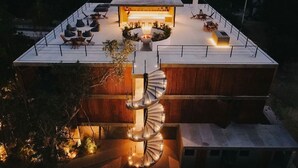 A modern building with a rooftop terrace featuring outdoor seating and a spiral staircase leading to an upper level. - Seremonia Origen by The Spot Rentals (Tulum)