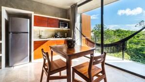 A modern kitchen with a built-in refrigerator, wooden cabinets, and a large window offering a view of lush greenery. - Seremonia Origen by The Spot Rentals (Tulum)