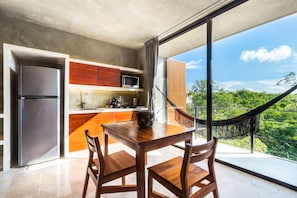 Enjoy a meal at the dining table with a view of lush greenery and a clear sky.