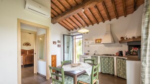 Une cuisine avec des meubles de rangement en bois, une table à manger avec des chaises et une fenêtre.