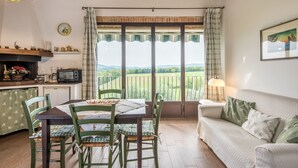 Une cuisine chaleureuse avec une table et des chaises, un canapé, une horloge et une vue sur la campagne.