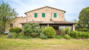 Un bâtiment en pierre avec un toit à deux versants, des volets verts et un porche abrité.