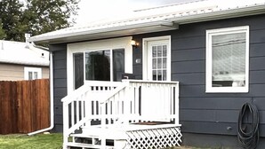 Une maison de plain-pied avec un porche à l’avant, une porte de garage bien visible et une cour clôturée.
