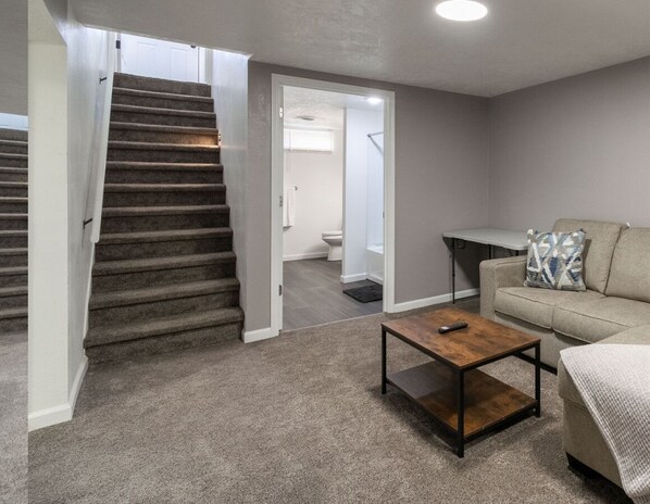 A living room with a staircase leading to a bathroom. - Bluebird House - Extended Stay (Great Falls)