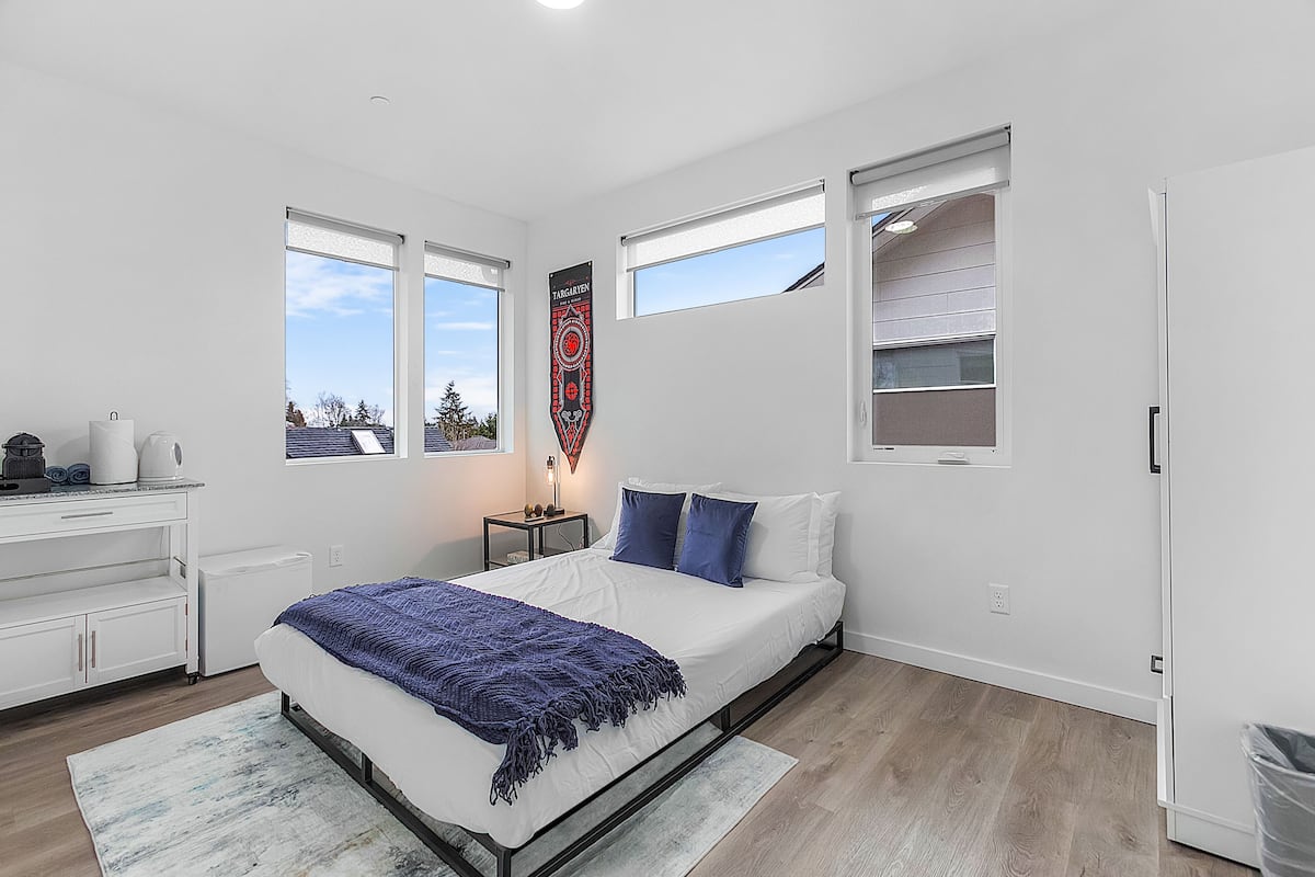 Une chambre à coucher moderne, avec un lit, une table de chevet, une commode et une fenêtre donnant sur un beau paysage.