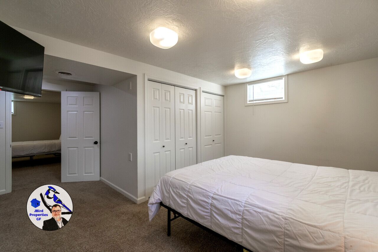 A bedroom with a bed, a closet, a window, and a door.