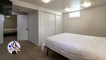A bedroom with a bed, a closet, a window, and a door.