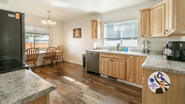 A kitchen with wooden cabinets, a granite countertop, a dishwasher, and a refrigerator. - Buffalo Jump Retreat - Extended Stay (Great Falls)