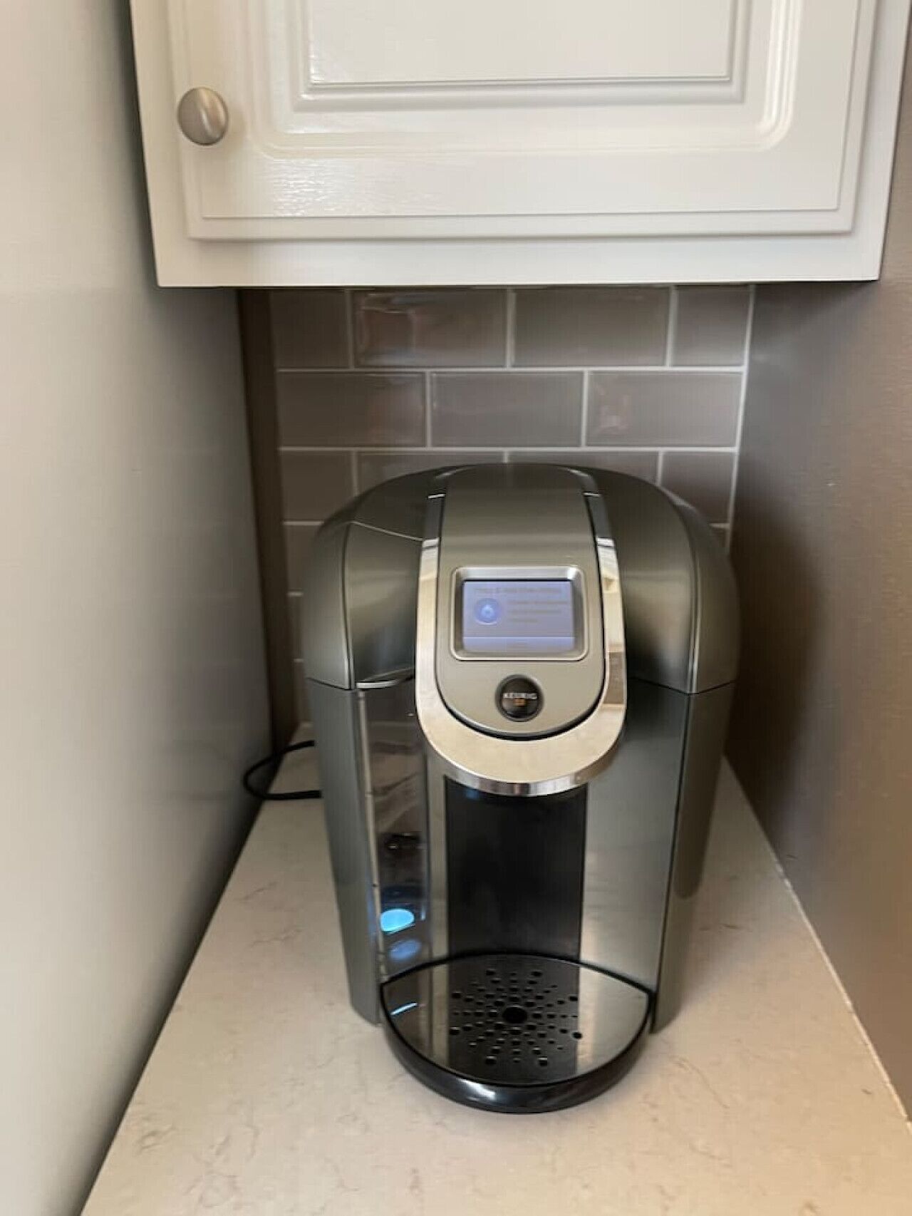 Eine Kaffeemaschine mit digitaler Anzeige, einer Bedienknop und einem Wasserbehälter.