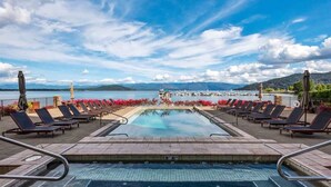 A pool area with lounge chairs and a view of a body of water and mountains. - Elevated Waterfront | Pool, Beach & Near Downtown (Sandpoint)