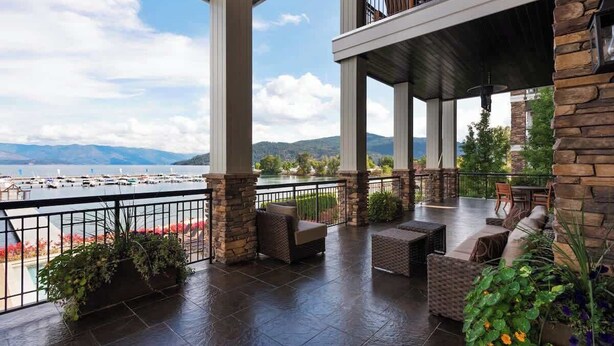 A covered outdoor patio with stone pillars, seating, and a view of a lake and mountains. - Elevated Waterfront | Pool, Beach & Near Downtown (Sandpoint)