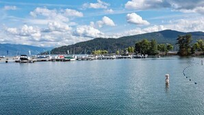 A marina with boats docked, a clear sky, and a forested hill in the background. - Elevated Waterfront | Pool, Beach & Near Downtown (Sandpoint)