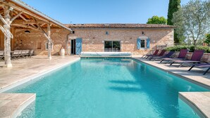 A swimming pool with a covered area and lounge chairs.