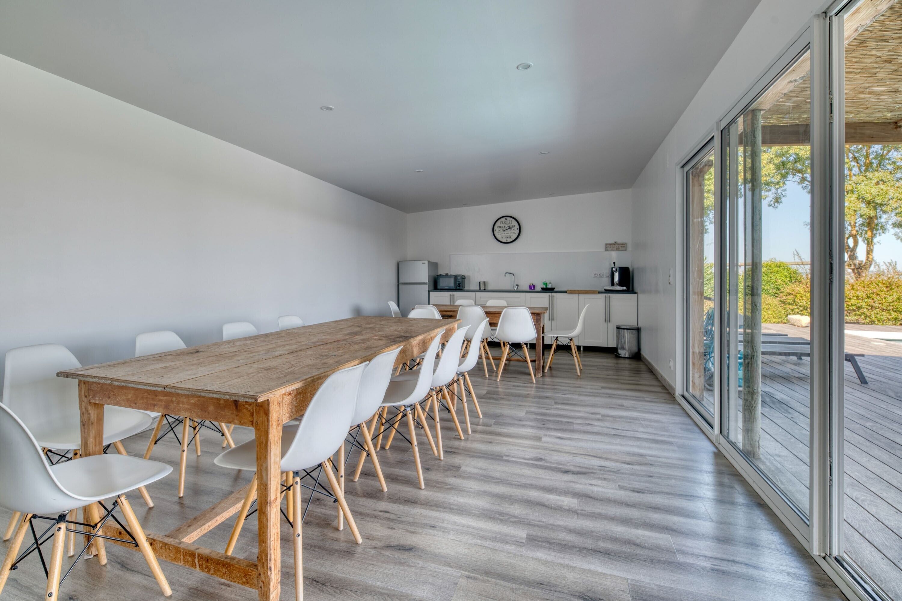 Eine moderne Küche mit weißen Schränken, einem Holztisch und weißen Stühlen.