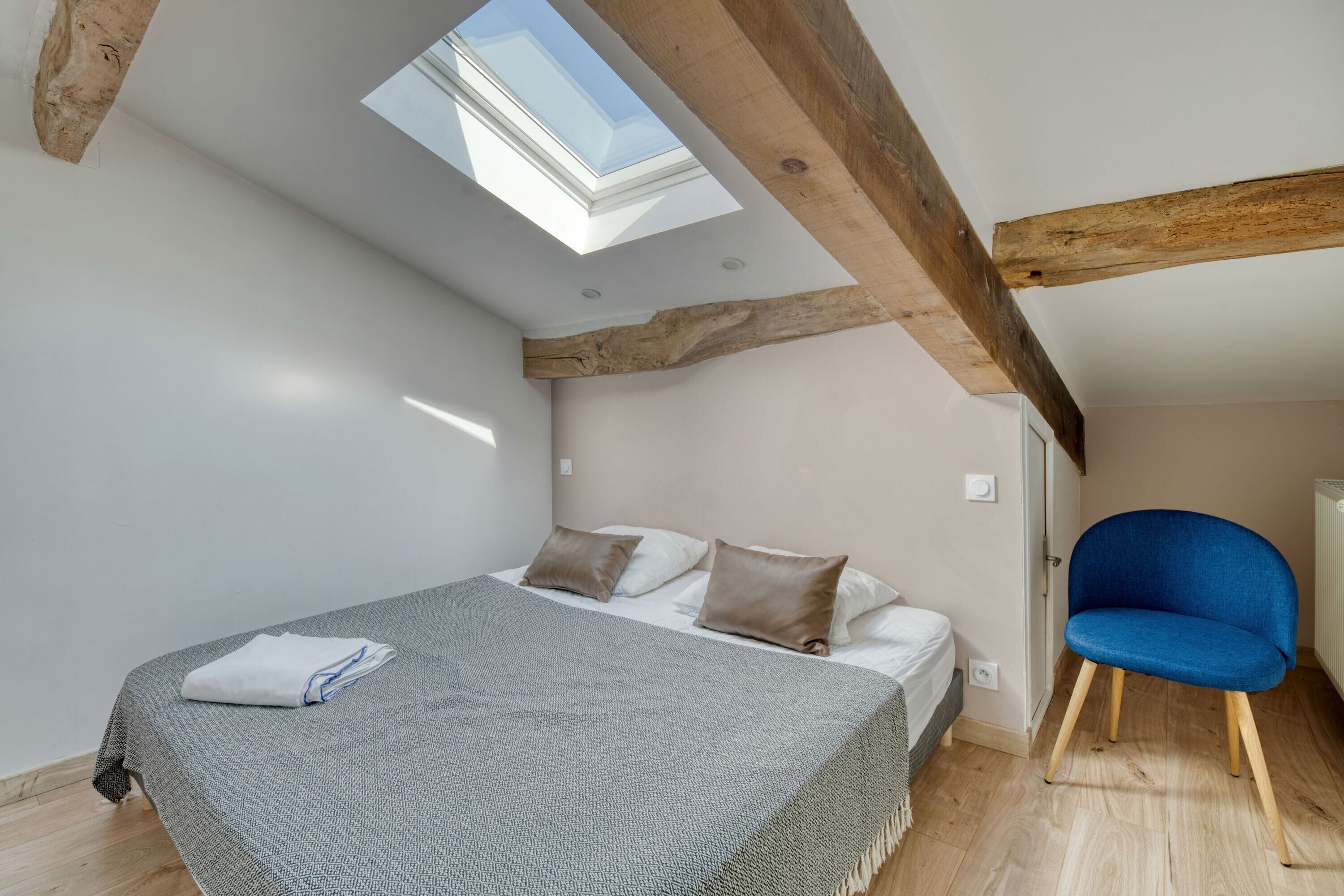 Ein Schlafzimmer mit Oberlicht, einem Bett, einem Sessel und einer Heizung.