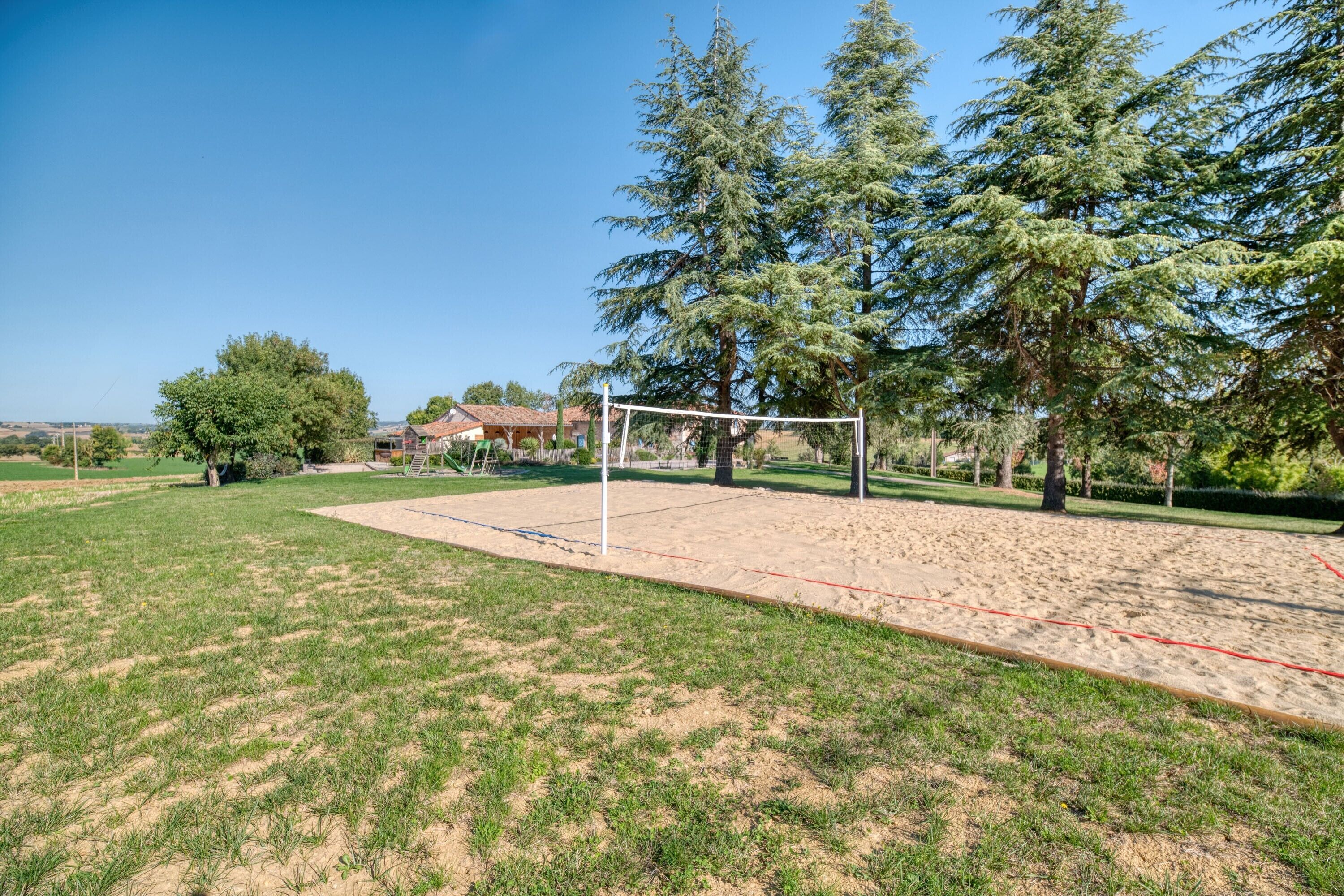 A sports field with a goalpost, surrounded by trees and a house in the background.