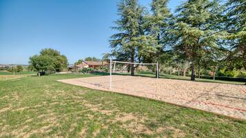 A sports field with a goalpost, surrounded by trees and a house in the background.