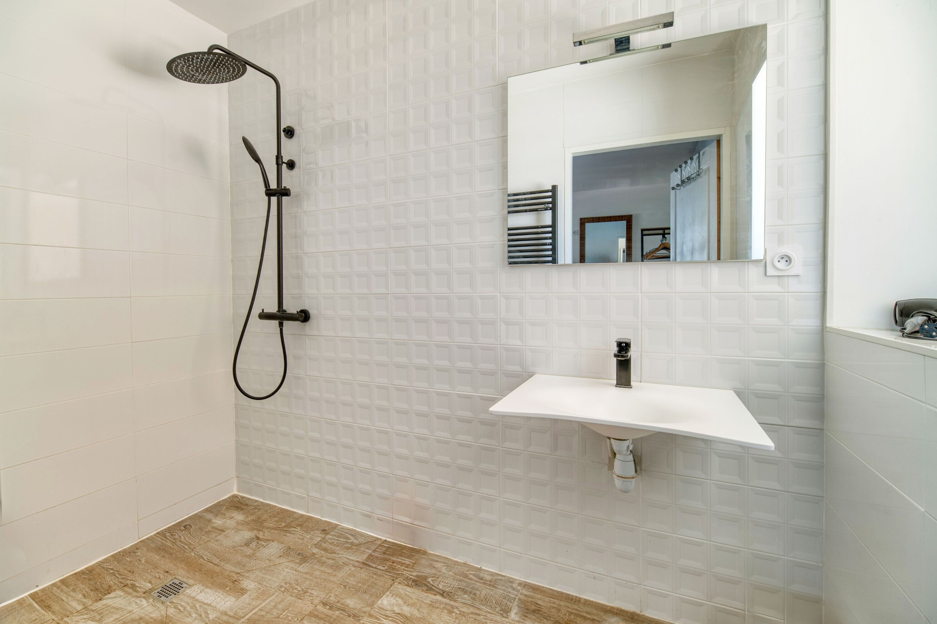 Un bagno con doccia, lavandino e specchio.