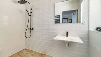 Un bagno con doccia, lavandino e specchio.