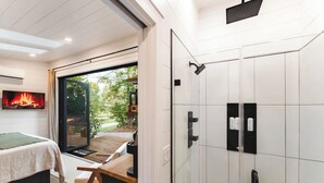 Quarto moderno com cama, televisão e porta de vidro deslizante que dá para um pátio.