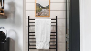 Casa de banho com um porta-toalhas, um quadro com uma paisagem e um armário escuro.