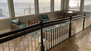 A spacious balcony with a view of the ocean, furnished with chairs and a table. - Life is better at the beach!  Stunning, oceanfront, corner-unit condominium. (Daytona Beach Shores)