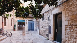 A narrow stone-paved alley with a bicycle parked on the left, a door on the right, and a building with a blue door in the background. - Bravissimo Catedral, with monumental views (Girona)