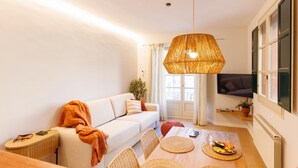 A modern living room with a sofa, a dining table with chairs, a hanging light fixture, and a TV mounted on the wall. - Bravissimo Catedral, with monumental views (Girona)