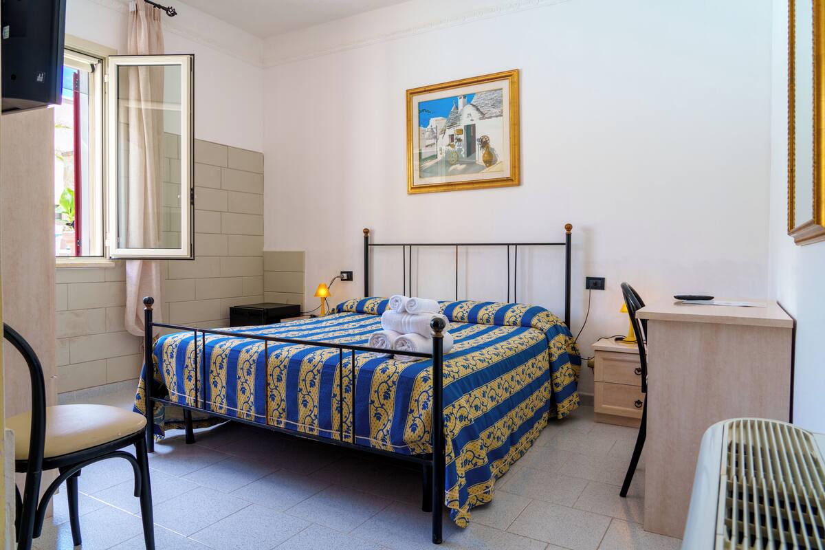Une chambre à coucher avec un lit, une chaise, un bureau et un tableau accroché au mur.