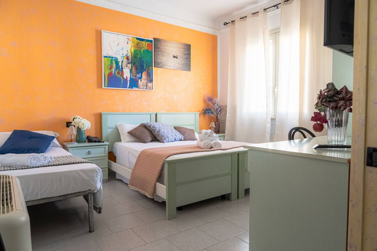 Une chambre d’h ôtel avec deux lits, un bureau et une fenêtre avec des rideaux.