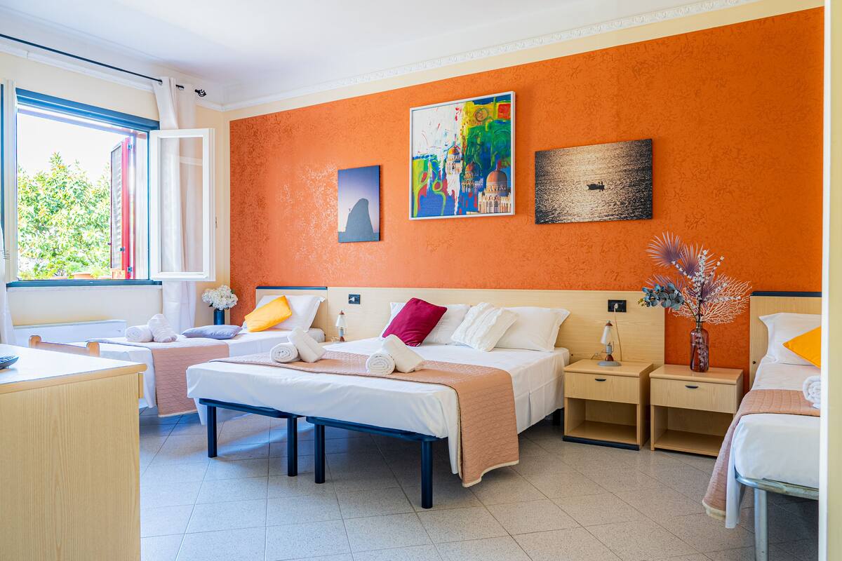 Une chambre d’hôtel avec un lit, des tables de chevet, un bureau et une fenêtre avec des rideaux.